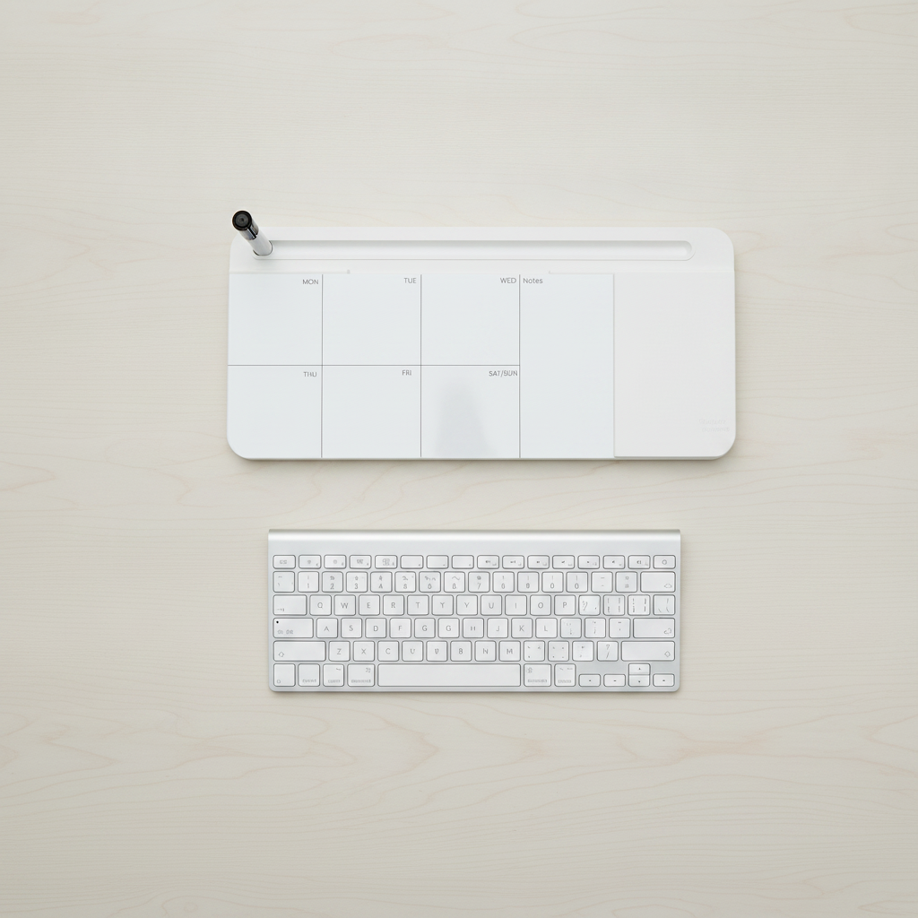 Overhead view of the glass desk whiteboard beside a full-size keyboard to compare their width