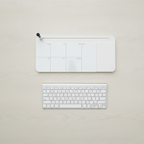 Overhead view of the glass desk whiteboard beside a full-size keyboard to compare their width