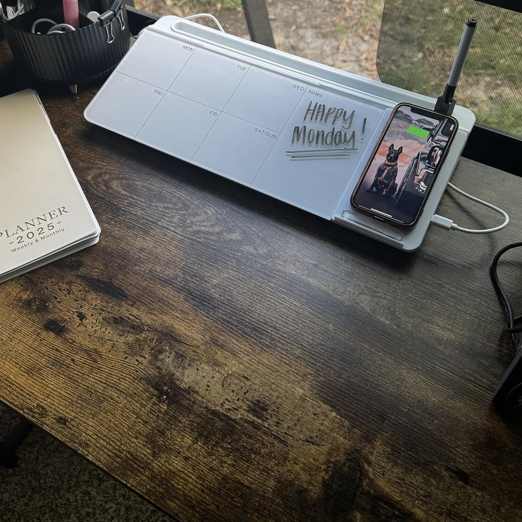 Customer photo of the glass desk whiteboard on a wooden desk with a handwritten note and a phone charging on the pad