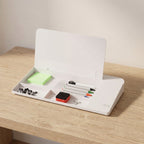 The glass lid lifted open, showing the organiser compartments underneath with sticky notes, binder clips, markers and the eraser