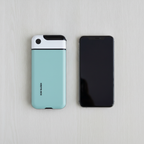 Overhead view of the mint lock box lying beside a smartphone to compare their size