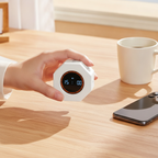 Hand holding the octagonal pomodoro timer next to a coffee mug and phone for size reference